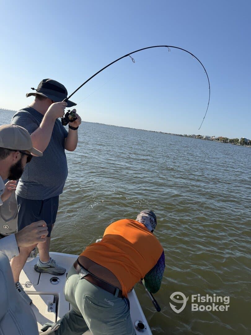 Anglers engaged in an exciting fishing moment, reeling in a catch on a sunny day in a coastal waterway.