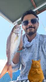 Angler proudly displaying a colorful Snapper while enjoying a day out on the water.