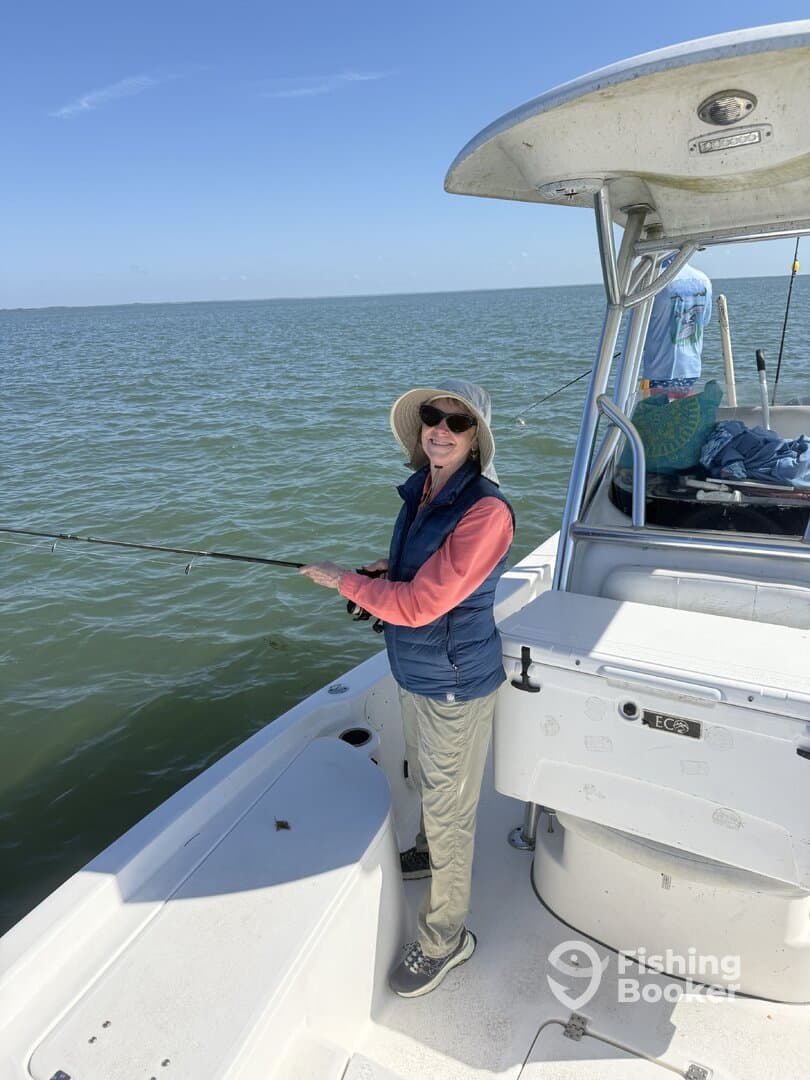 A woman casting her line while fishing on a boat in calm waters, enjoying a sunny day on the water.