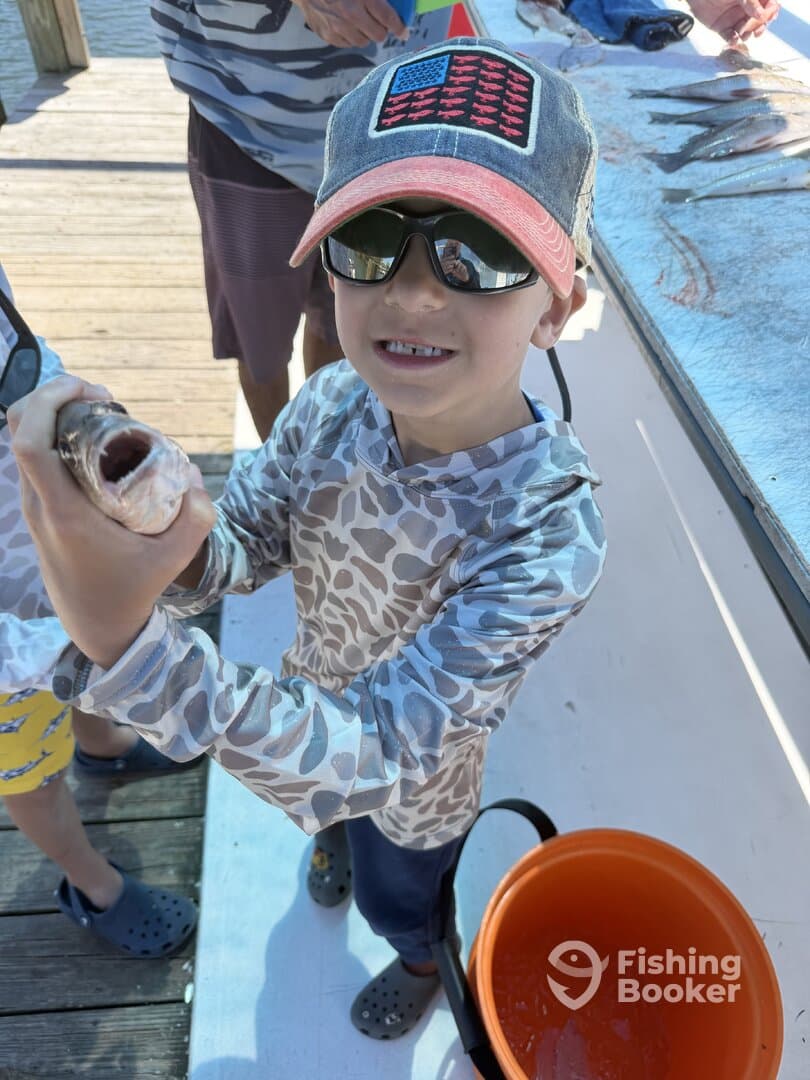 A young angler proudly displaying a fish at the dock, showcasing a fun family fishing experience.