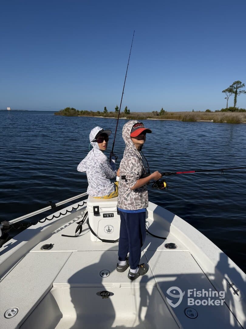 Two young anglers fishing from a boat in calm waters, showcasing a fun day on the water.