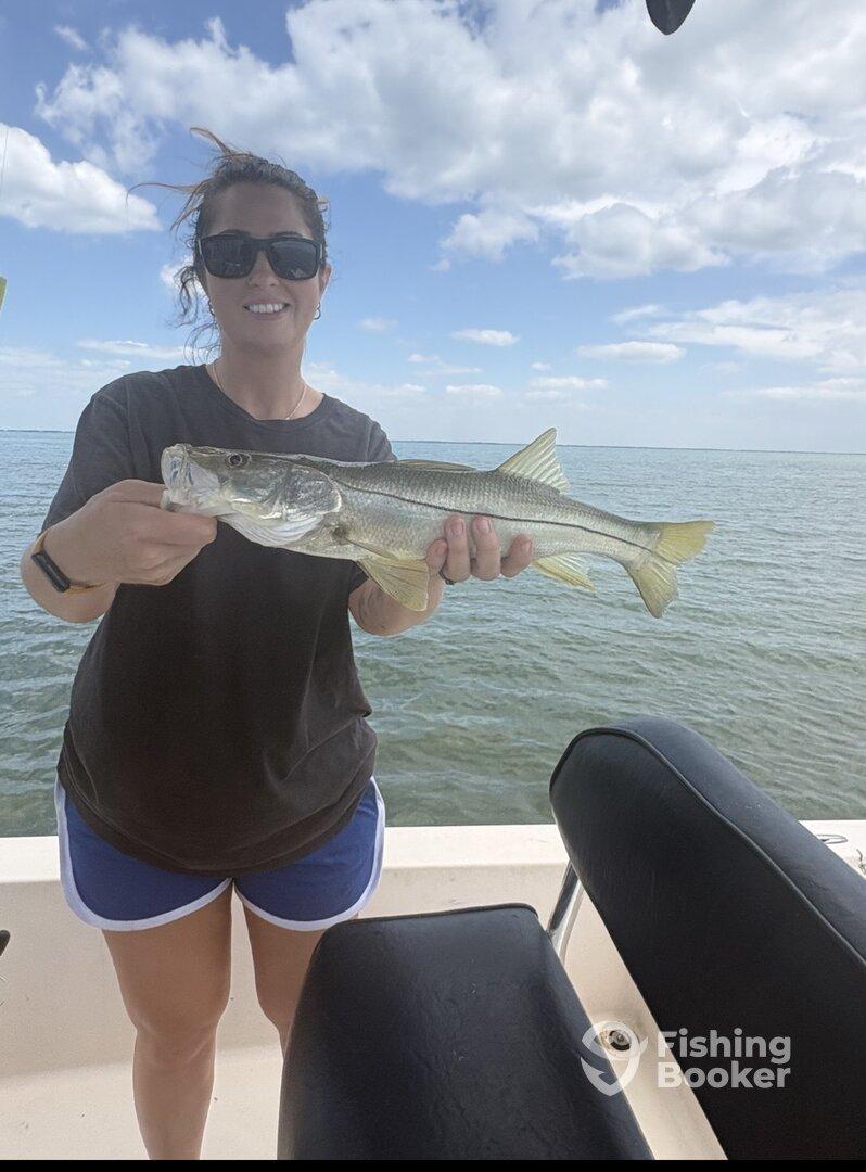 Angler proudly displaying a Snook caught during a fishing trip on the water.