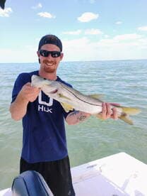 Angler proudly displaying a Snook while fishing on a sunny day in coastal waters.
