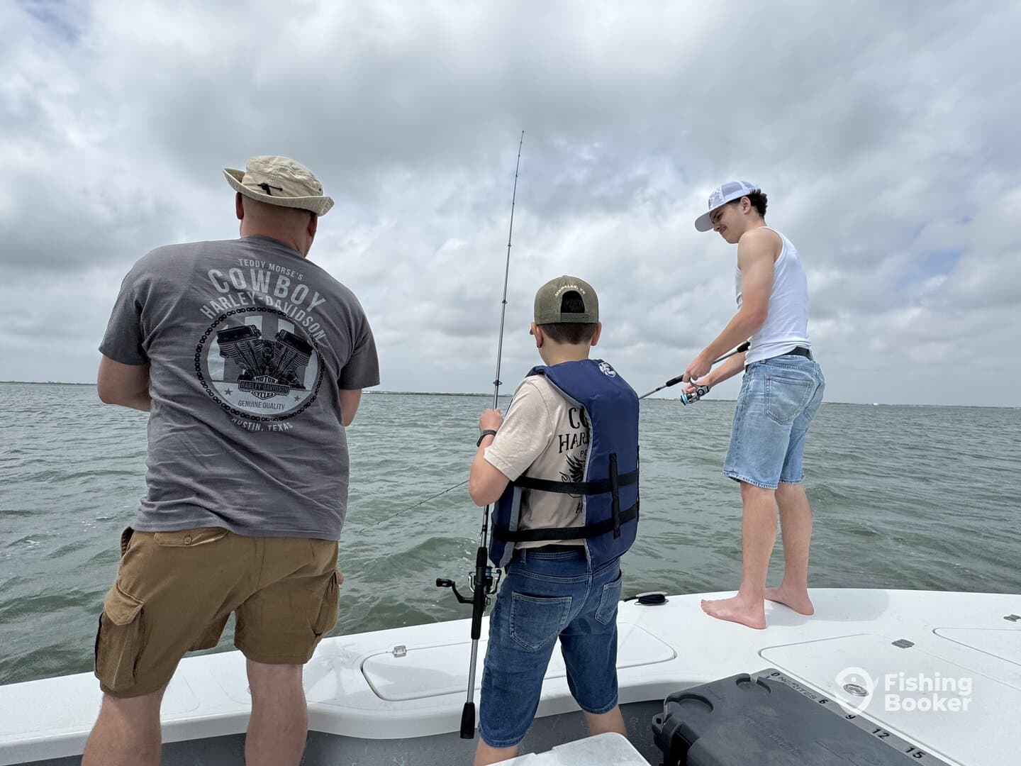 A family fishing trip in a coastal setting, featuring a young boy and two adults actively fishing from the boat.
