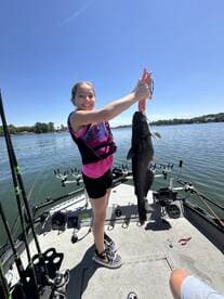 A young angler proudly displaying a large catfish while fishing on a sunny day.