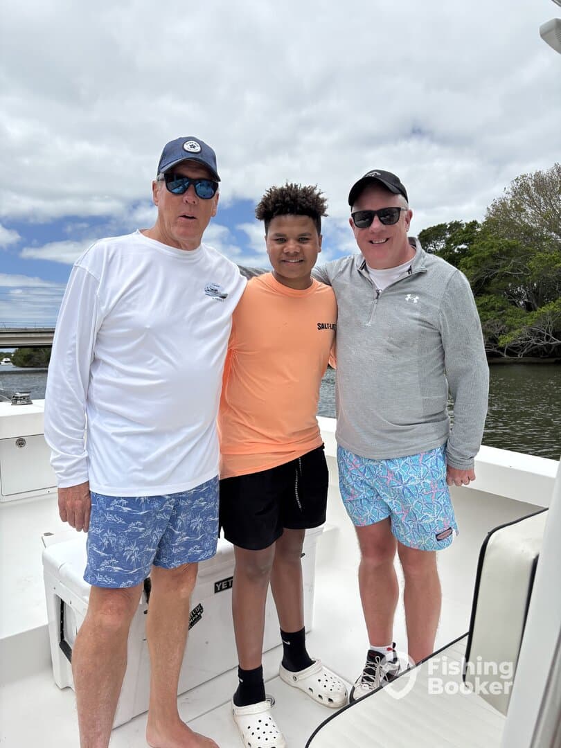 Three anglers posing together on a boat, enjoying a fishing trip.