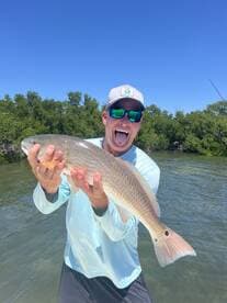 A proud angler displaying a large Redfish while enjoying a sunny day on the water.