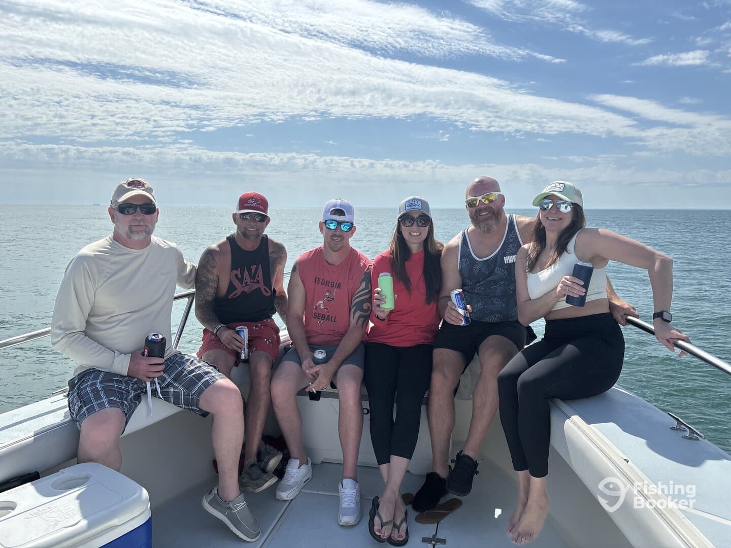 A group of friends enjoying a day out on the water, relaxing on the deck of a fishing boat with drinks in hand.