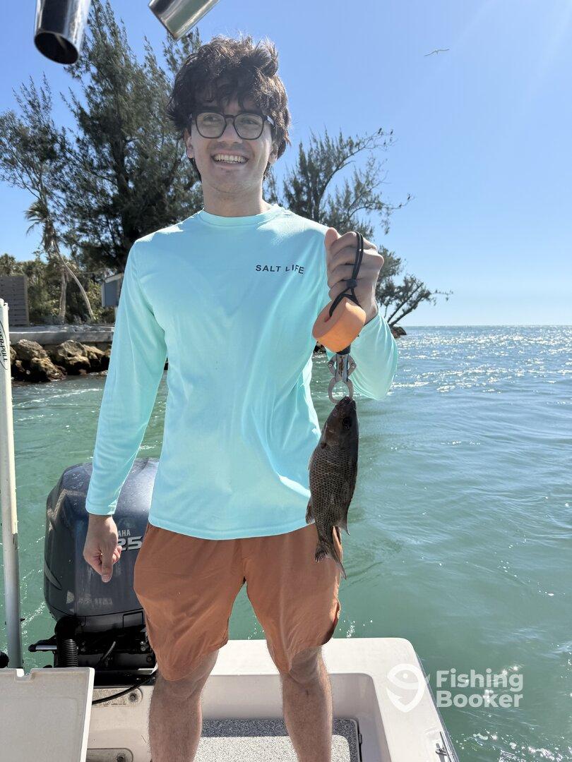 A young angler proudly displaying a freshly caught fish while enjoying a sunny day on the water.