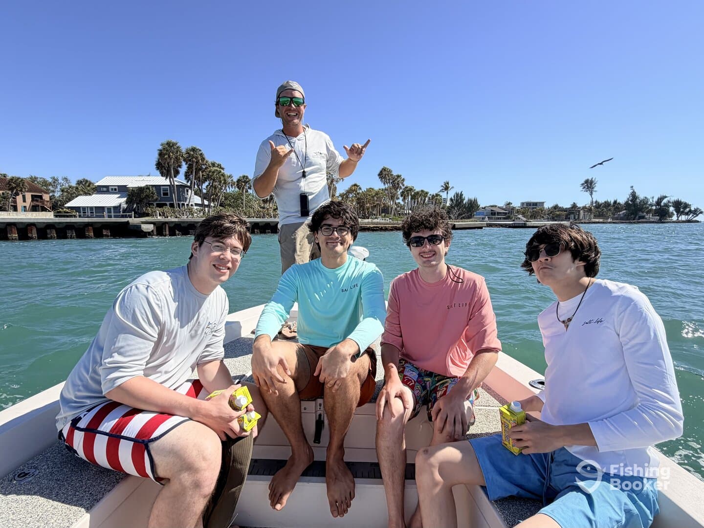 Group of young adults enjoying a day on the boat, with a scenic waterfront in the background.