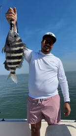 Angler proudly displaying a Sheepshead caught during a sunny day on the water.