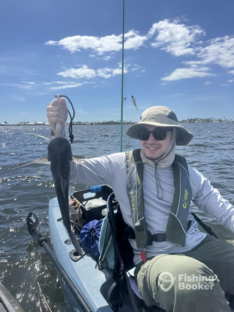Angler holding a Black Drum while kayaking in a sunny coastal environment.