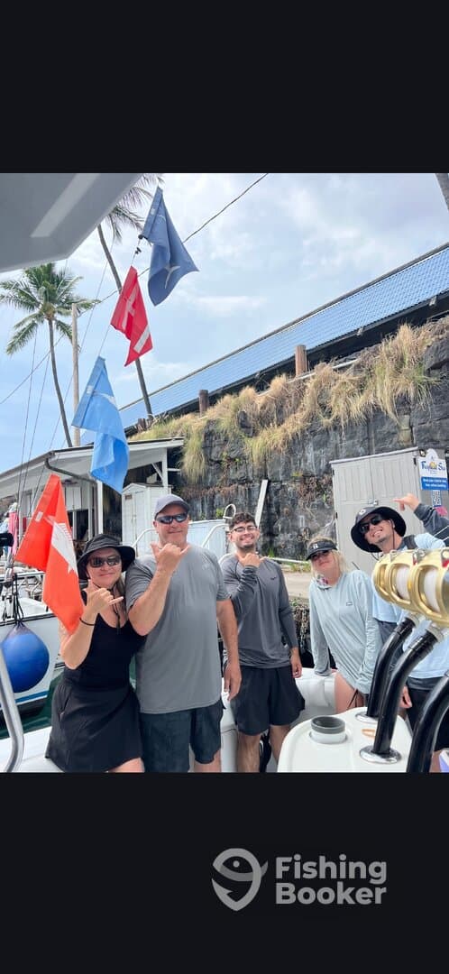 Group of anglers posing on a boat with flags in the background, showcasing a fun day on the water.