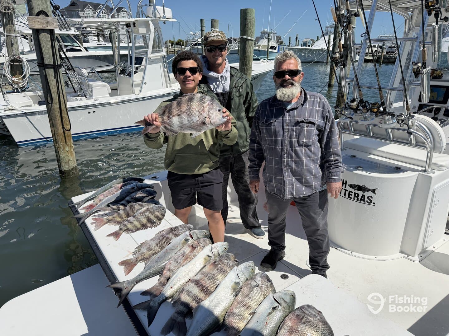 A family group proudly displaying their catch of various fish, including a large Snapper, on the deck of a fishing boat.