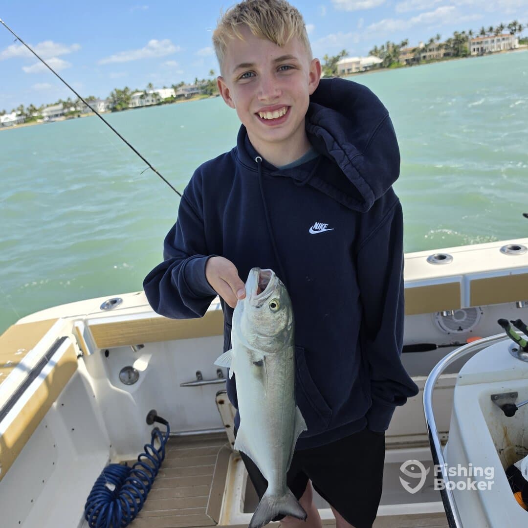 Young angler proudly holding a large fish while fishing on a boat, showcasing a successful catch in a coastal environment.