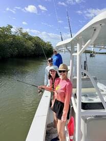 A group of anglers enjoying a fishing trip on a boat, casting lines in a scenic mangrove area.