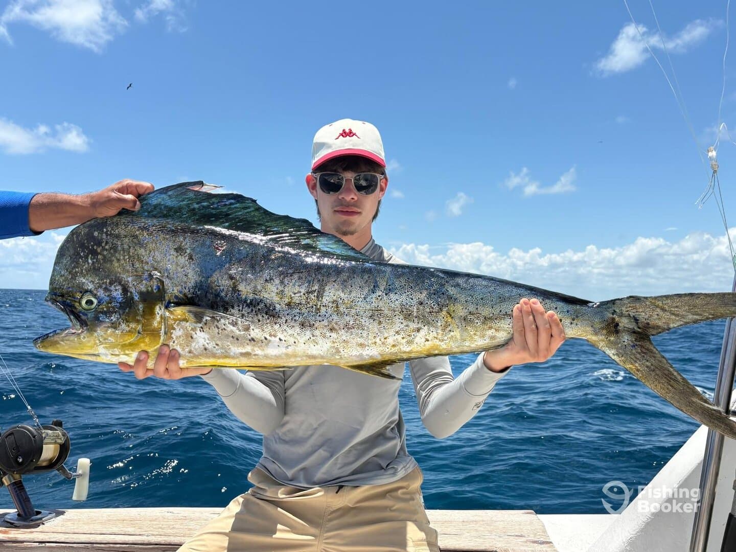 A young angler proudly displaying a large Mahi Mahi while fishing offshore, showcasing a successful day on the water.