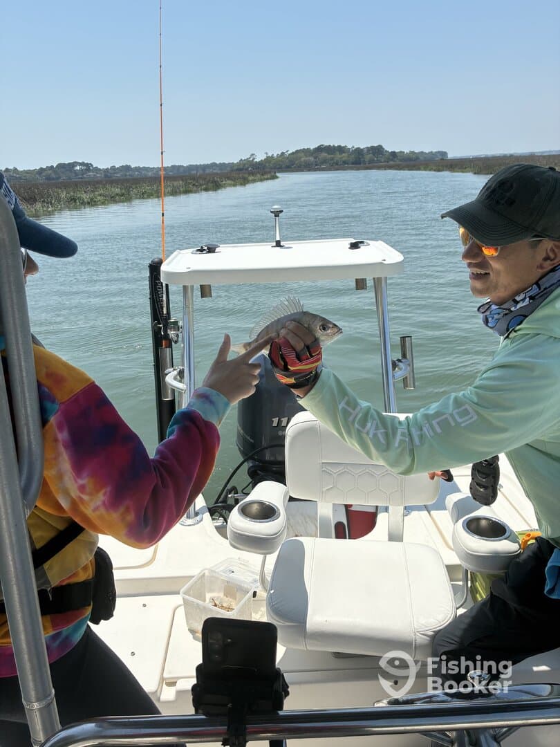 Two anglers joyfully displaying a caught fish while enjoying a day on the water, showcasing a vibrant fishing environment.