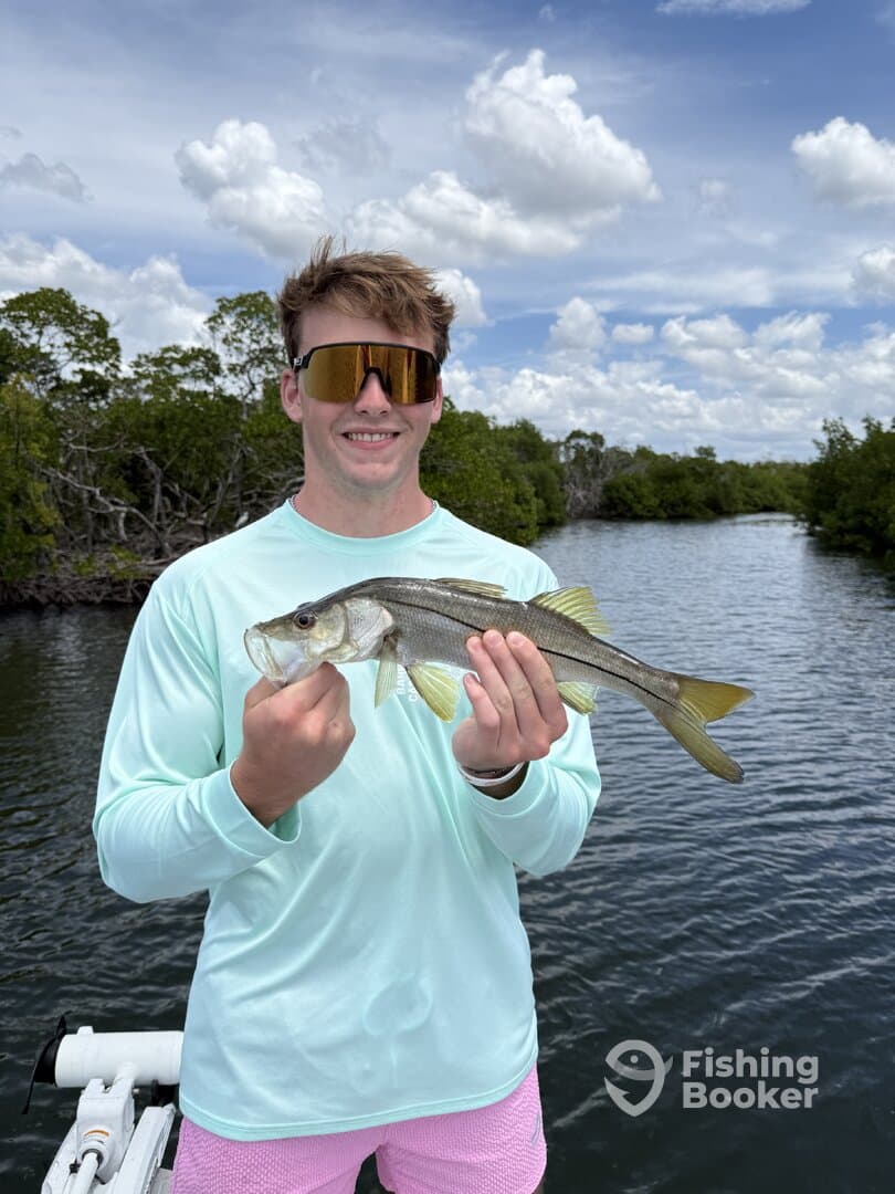 Angler proudly displaying a Snook while fishing in a mangrove-lined waterway.