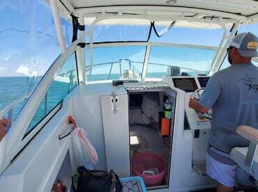 The captain navigates the boat from the helm, showcasing a well-equipped interior with a clear view of the ocean.