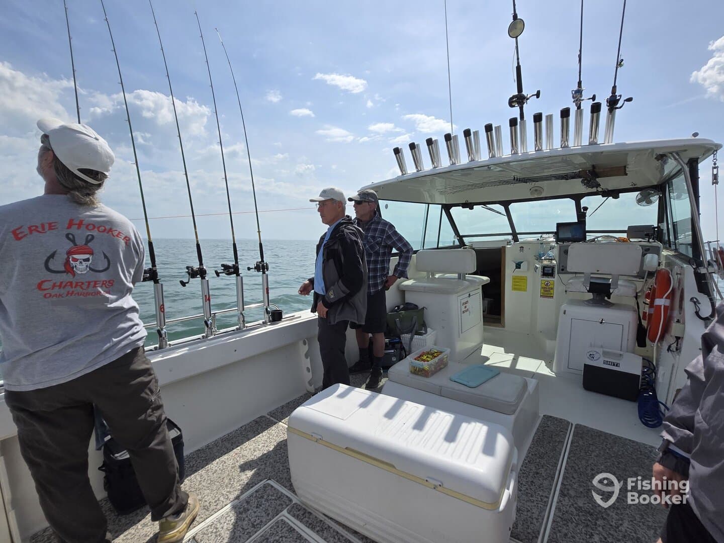 Interior view of a fishing charter boat with anglers preparing for a day on the water, featuring multiple fishing rods and a spacious cabin.