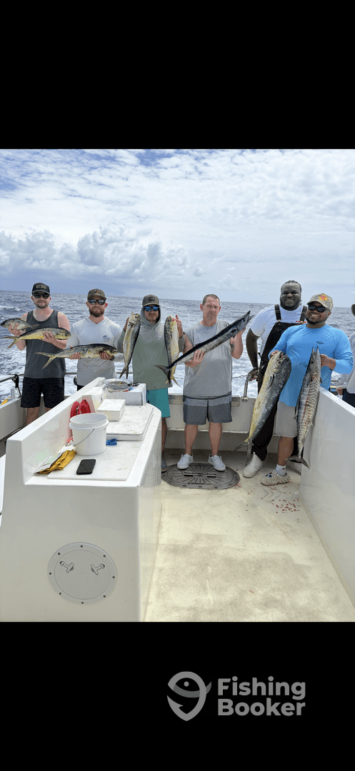A group of anglers proudly displaying their catch of Mahi Mahi aboard a fishing charter in open waters.