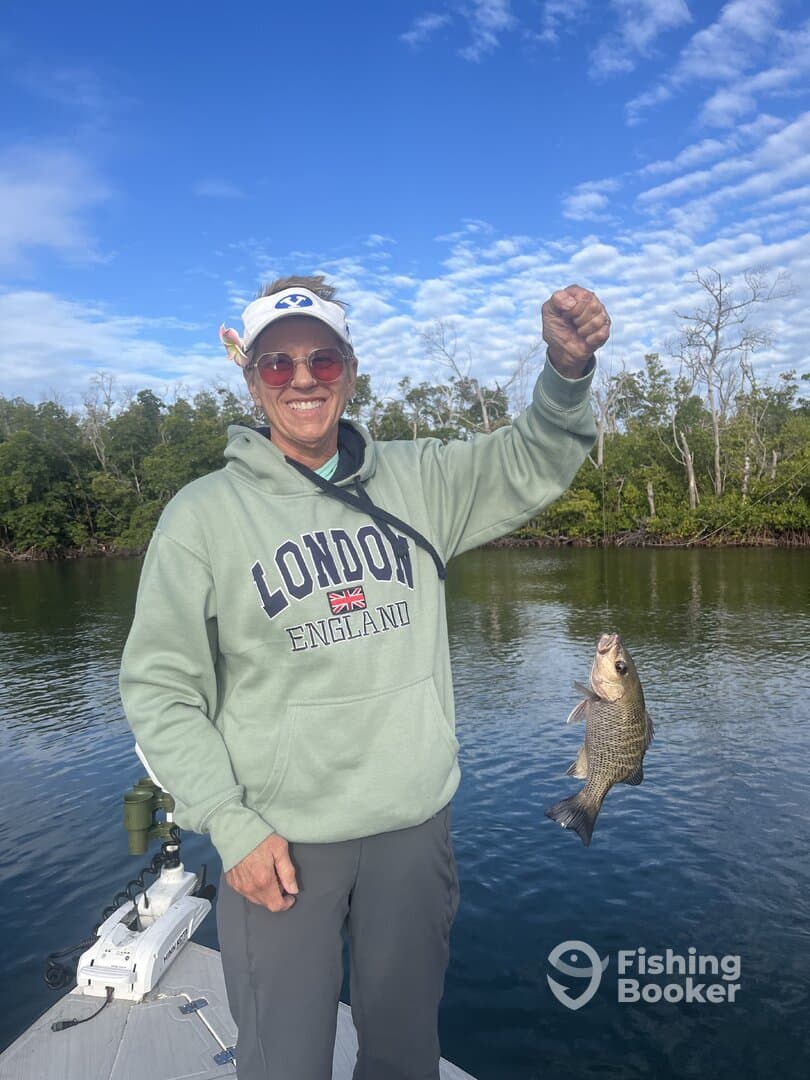 An angler proudly displaying a freshly caught Crappie while fishing on a calm waterway, surrounded by lush greenery.