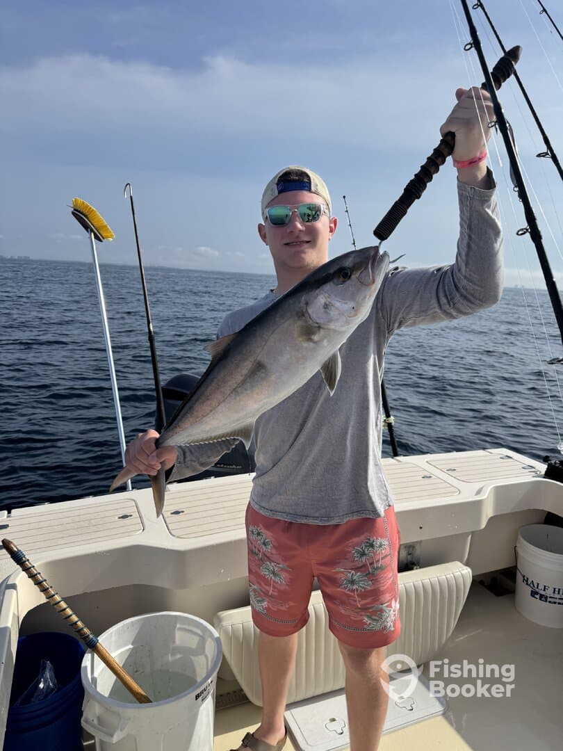 A young angler proudly displaying a large fish while fishing on a boat in open waters.