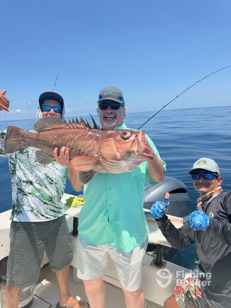 Group of anglers celebrating a successful catch of a large Red Grouper while out on the open water.