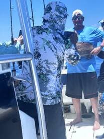 A group of anglers celebrating a successful catch aboard a fishing boat, with one person proudly displaying a large fish.