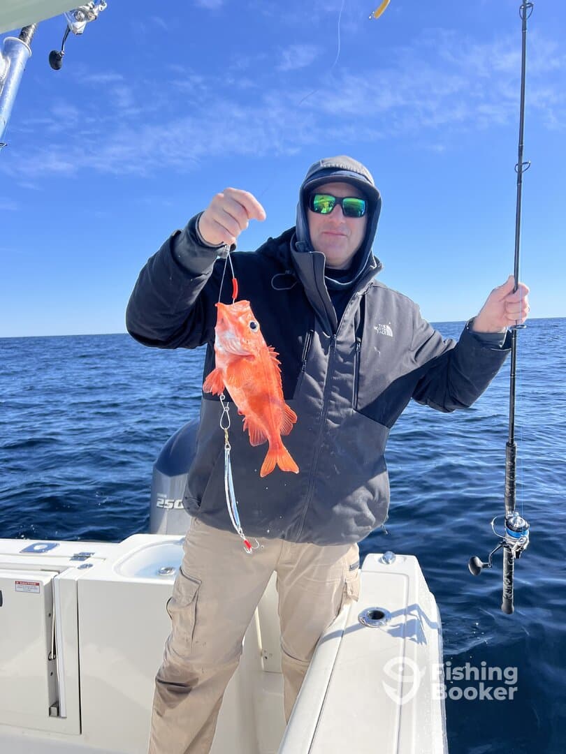 Angler proudly displaying a vibrant Red Snapper while fishing offshore, showcasing a successful catch in clear blue waters.