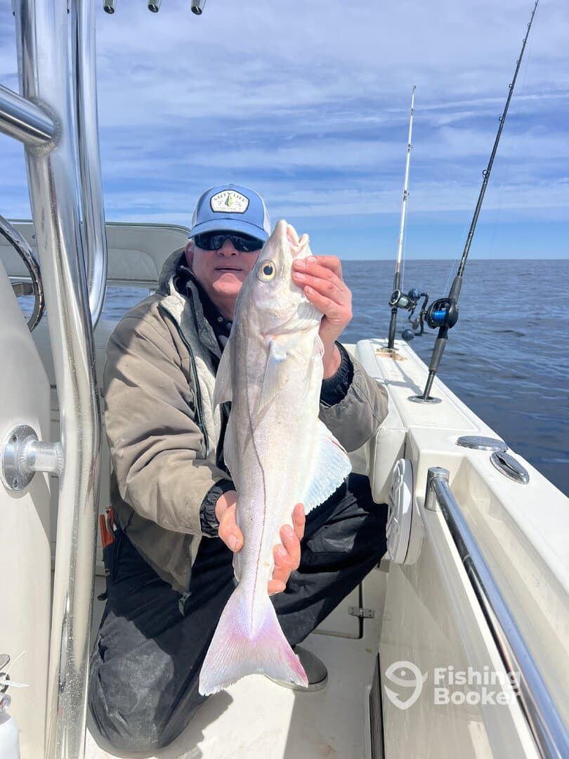 Angler proudly displaying a large Halibut while fishing offshore, showcasing the excitement of a successful catch.