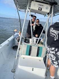 Two anglers proudly displaying a caught fish aboard a fishing boat, enjoying a day on the water.