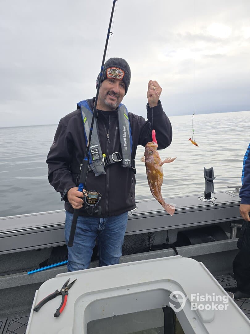 Angler proudly displaying a freshly caught fish while fishing on a boat in open water.