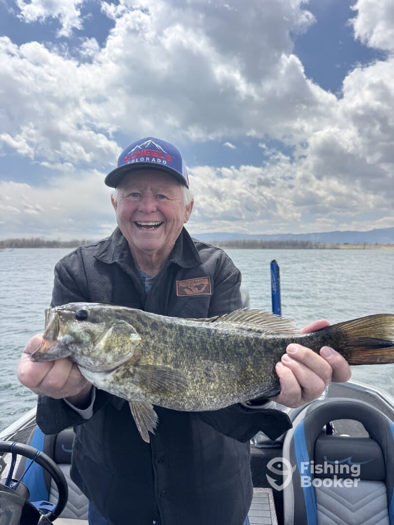 An enthusiastic angler proudly displaying a large Largemouth Bass while fishing on a scenic lake.
