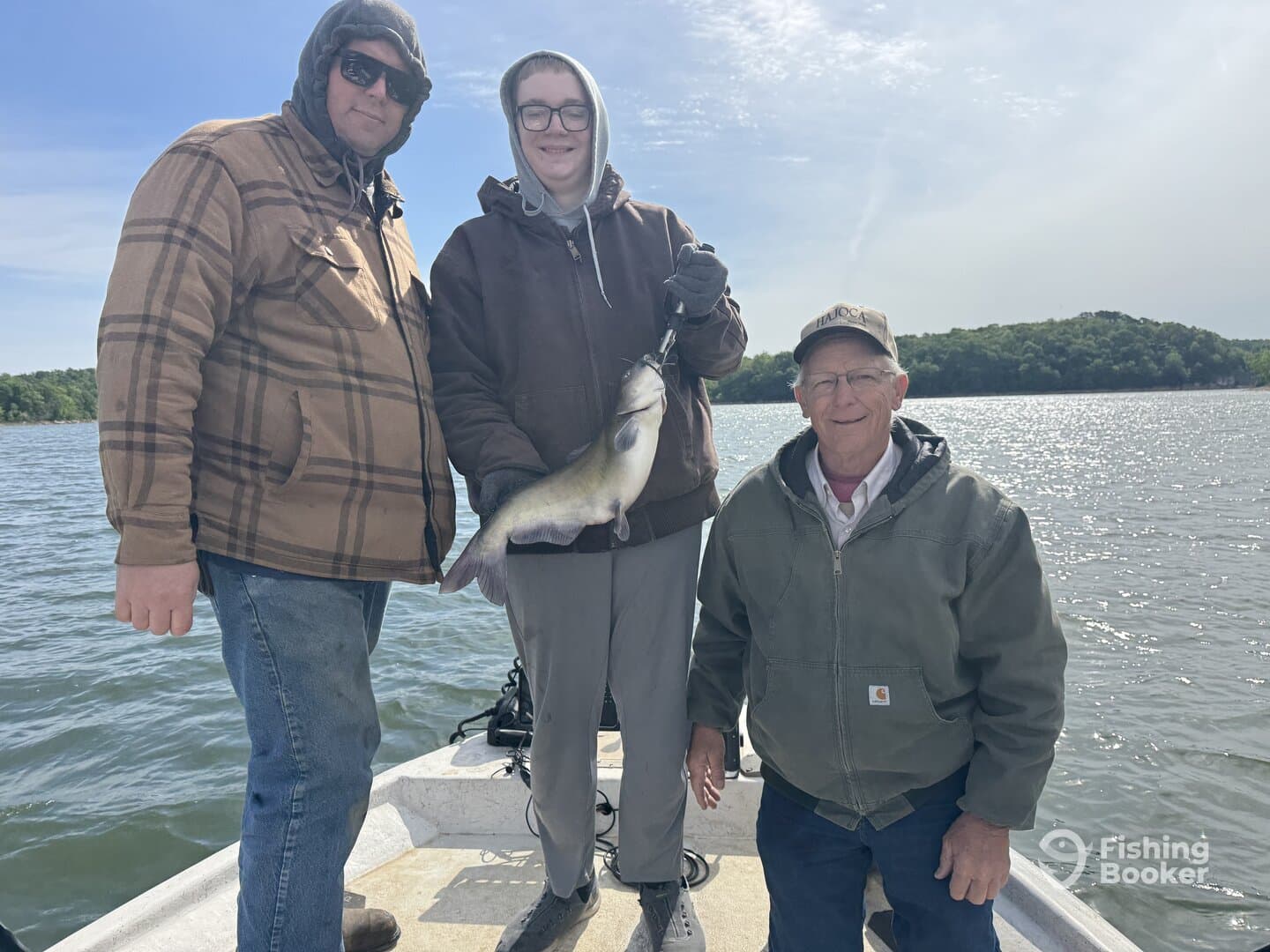 A family trio proudly displaying a large catfish while enjoying a day on the water.