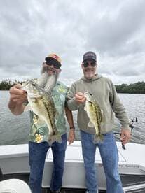 Two anglers proudly displaying their catch of large Largemouth Bass while fishing on a lake.
