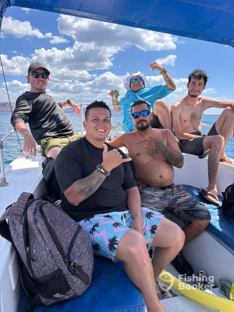 Group of friends enjoying a day on the boat, relaxing under the sun with scenic views of the water and clouds.