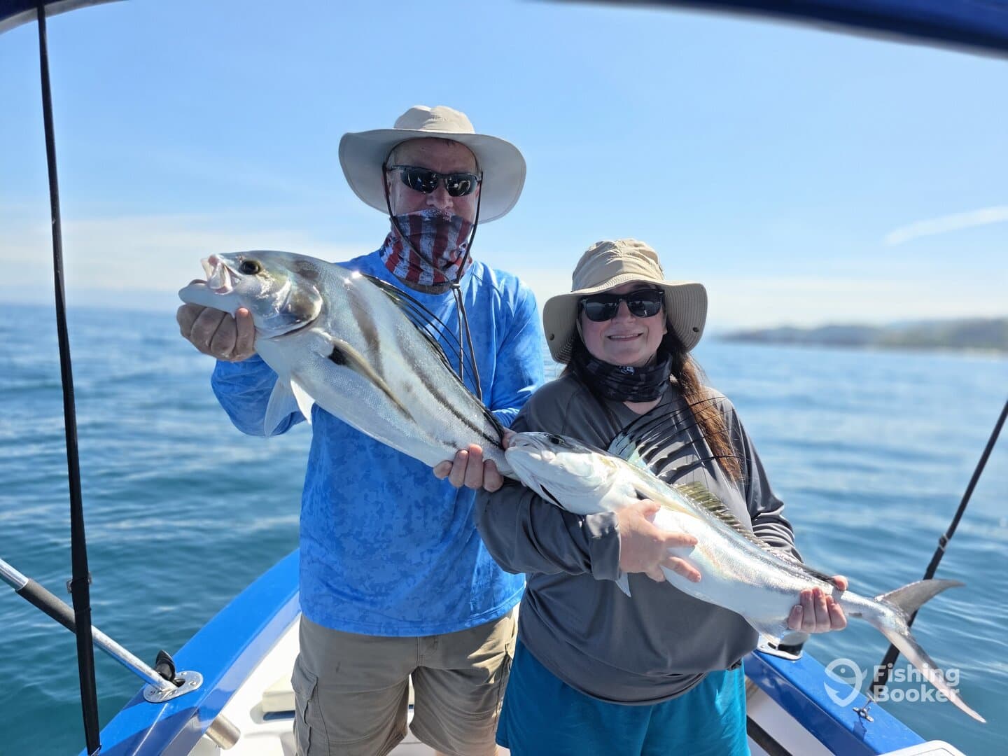 A couple proudly displaying their catch of striped bass while enjoying a sunny day on the water.