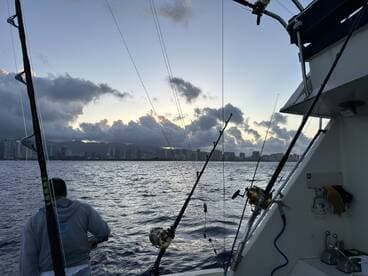 A fisherman prepares for a day on the water, with the city skyline in the background and fishing rods ready for action.