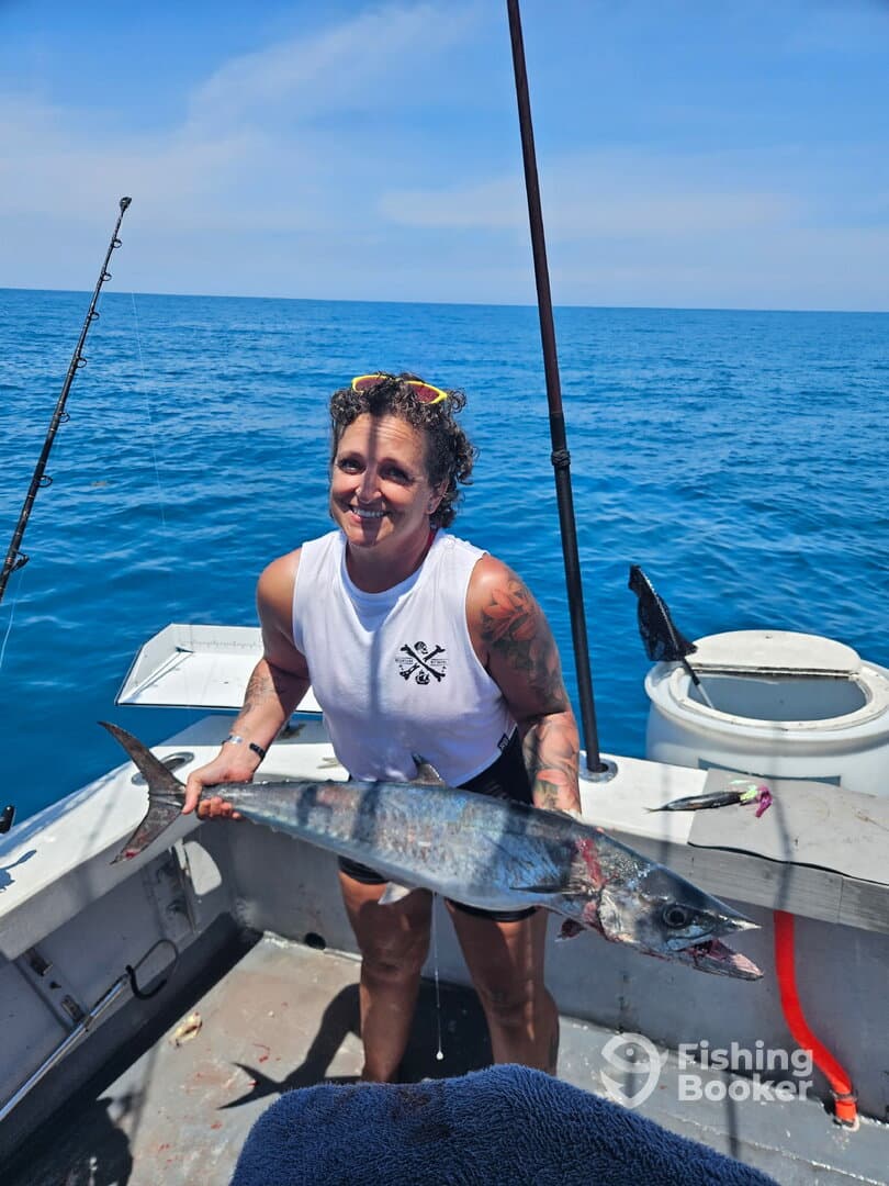 Angler proudly displaying a large fish on a sunny day while fishing offshore.