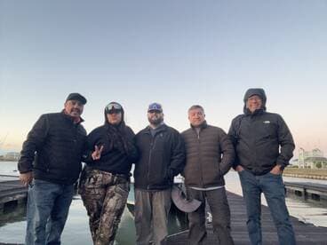 Group of five anglers posing together at the dock, showcasing camaraderie before their fishing adventure.