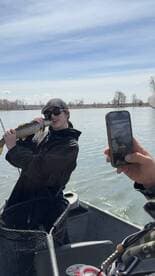 Angler proudly holding a large trout while fishing on a scenic river, capturing the moment with a friend.