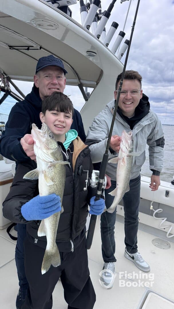A young angler and his family proudly displaying their catch of Walleye while fishing on a boat.