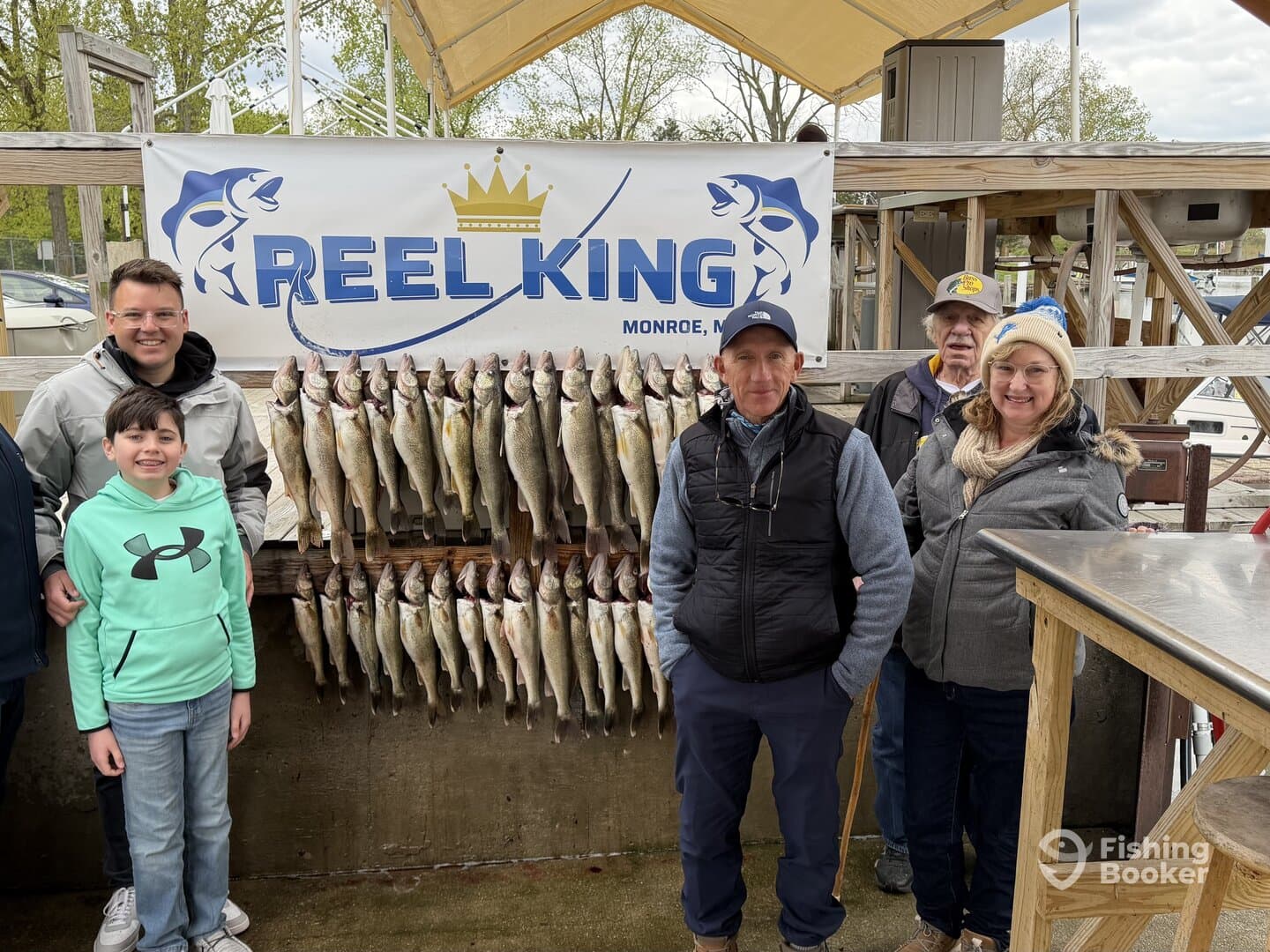 A family proudly poses in front of a catch board displaying an impressive haul of Walleye at Reel King in Monroe, Michigan.