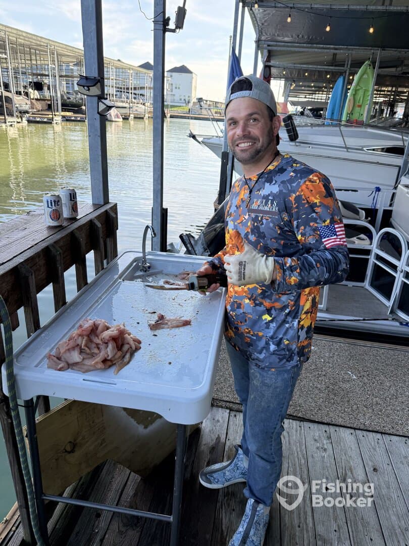 Angler preparing freshly caught fish at a cleaning station by the dock, showcasing a variety of fillets.