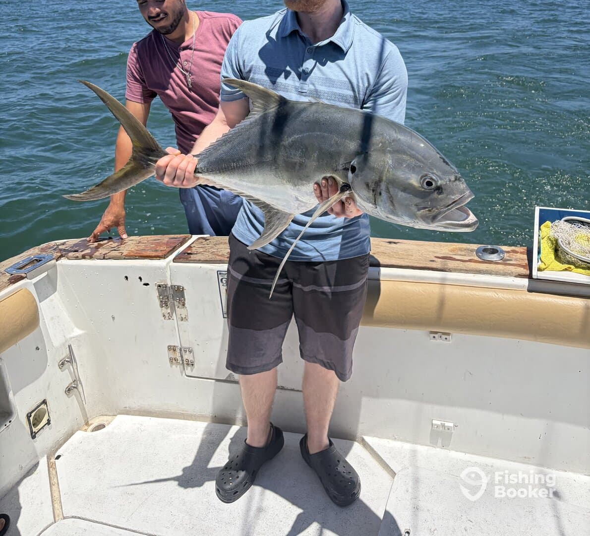 Angler proudly displaying a large fish on a boat, showcasing a successful fishing trip.
