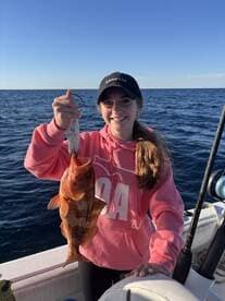 A young angler proudly displaying a large Red Grouper while fishing offshore, showcasing a beautiful day on the water.