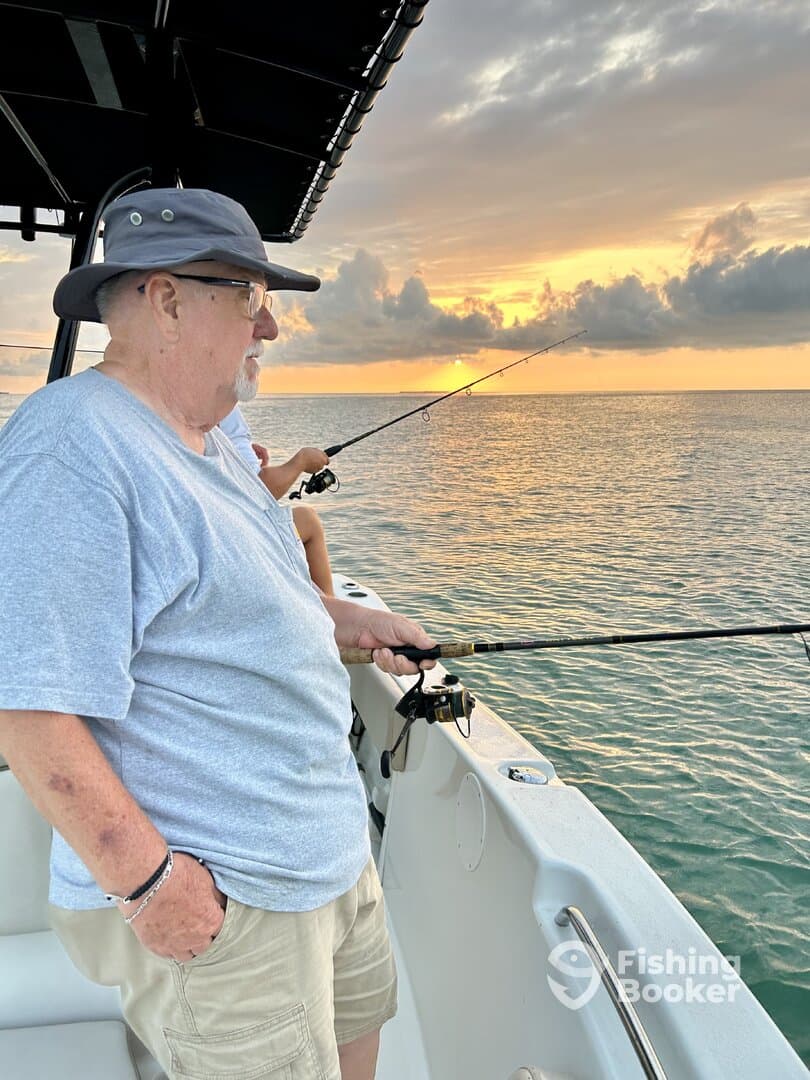Two anglers fishing at sunset from a boat, enjoying a tranquil evening on the water.