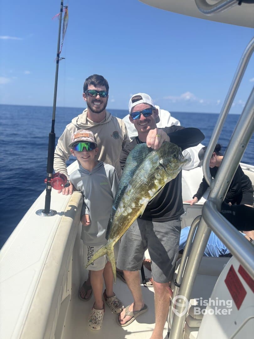 A family enjoying a successful fishing trip, proudly displaying a large Mahi Mahi on a boat in open waters.